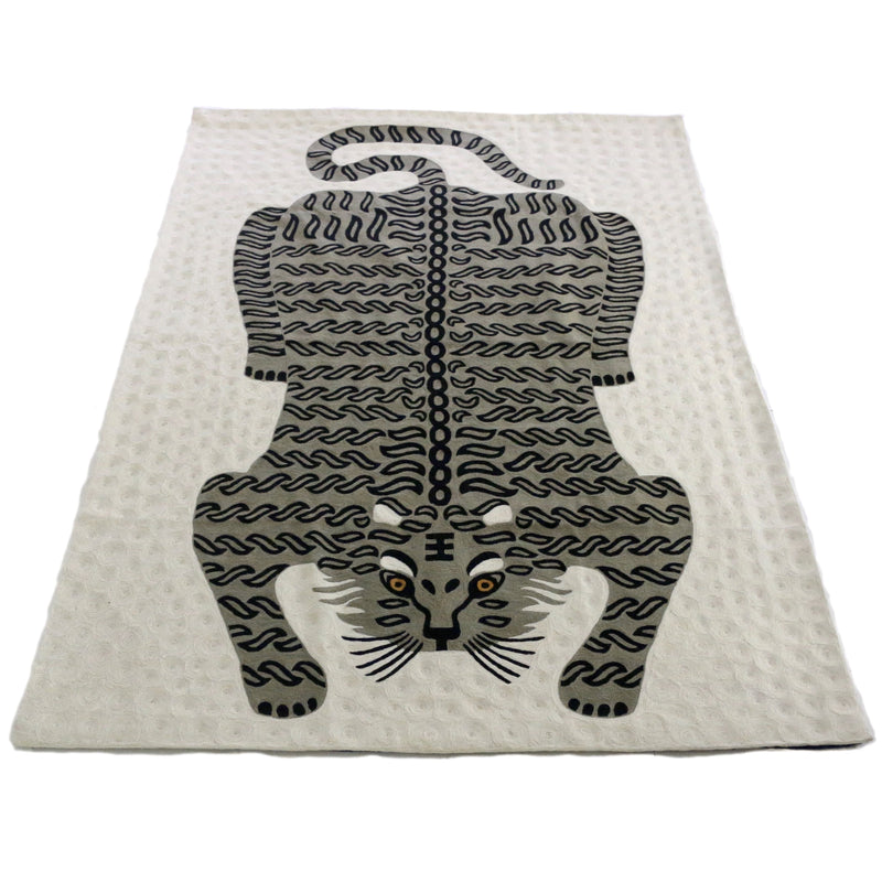 Bengal Tiger Carpet Ivory. Each carpet is made by hand by skilled artisans in Kashmir, the most northern part of India. Using a technique called chainstitch, colourful pure wool yarn is stitched by hook through cotton. Each carpet takes up to two months to complete.   We are stocking these beautiful carpets in a selection of bold colours in very small quantities. This special one is a grey tiger on an ivory background.